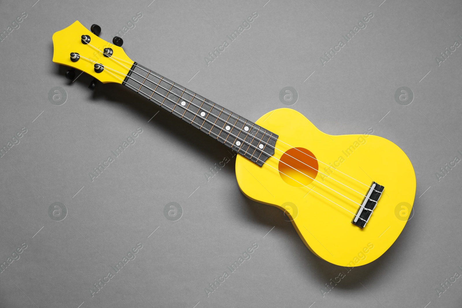 Photo of One ukulele on grey background, top view