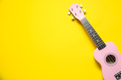 Photo of One ukulele on yellow background, top view. Space for text