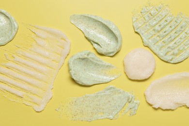 Photo of Samples of different body scrubs on yellow background, top view