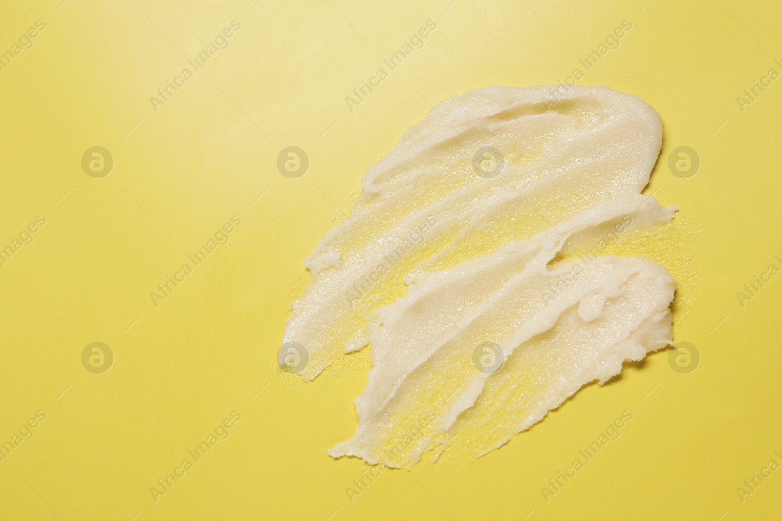 Photo of Sample of body scrub on yellow background, top view. Space for text