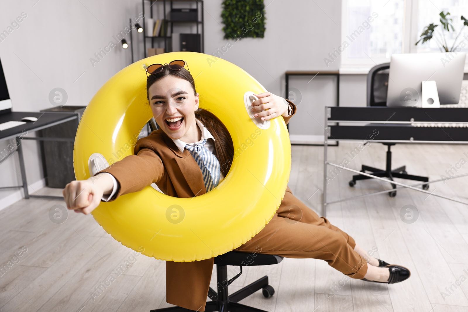 Photo of Businesswoman with inflatable ring and sunglasses posing on chair in office