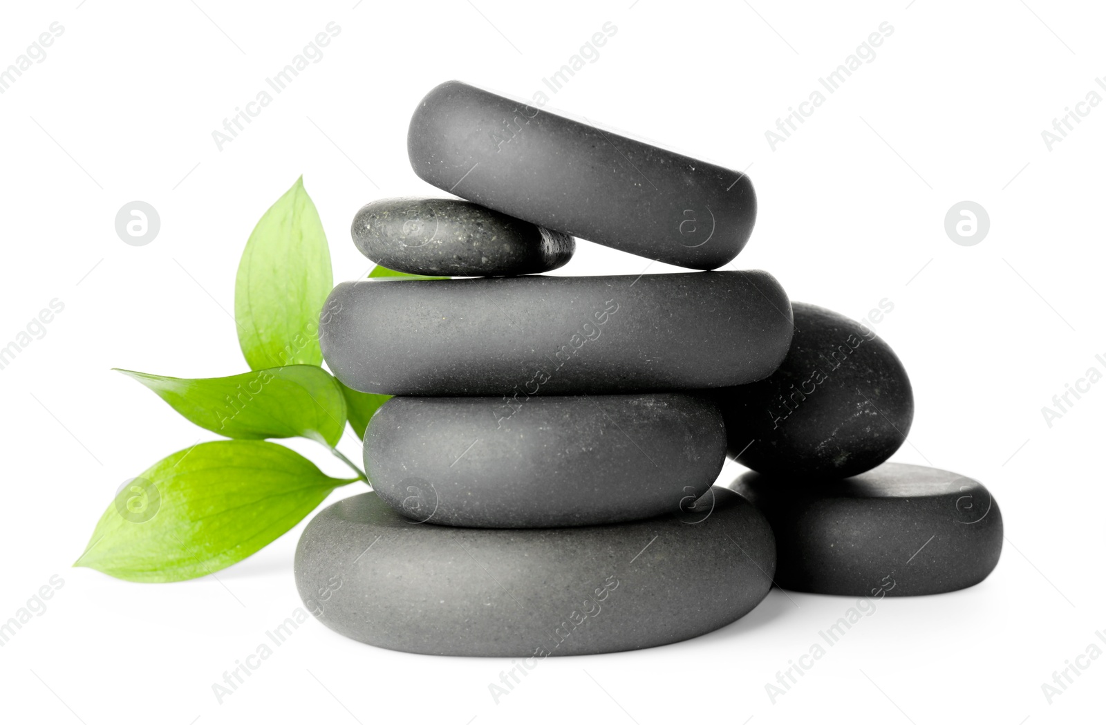 Photo of Stacked spa stones and green leaves isolated on white