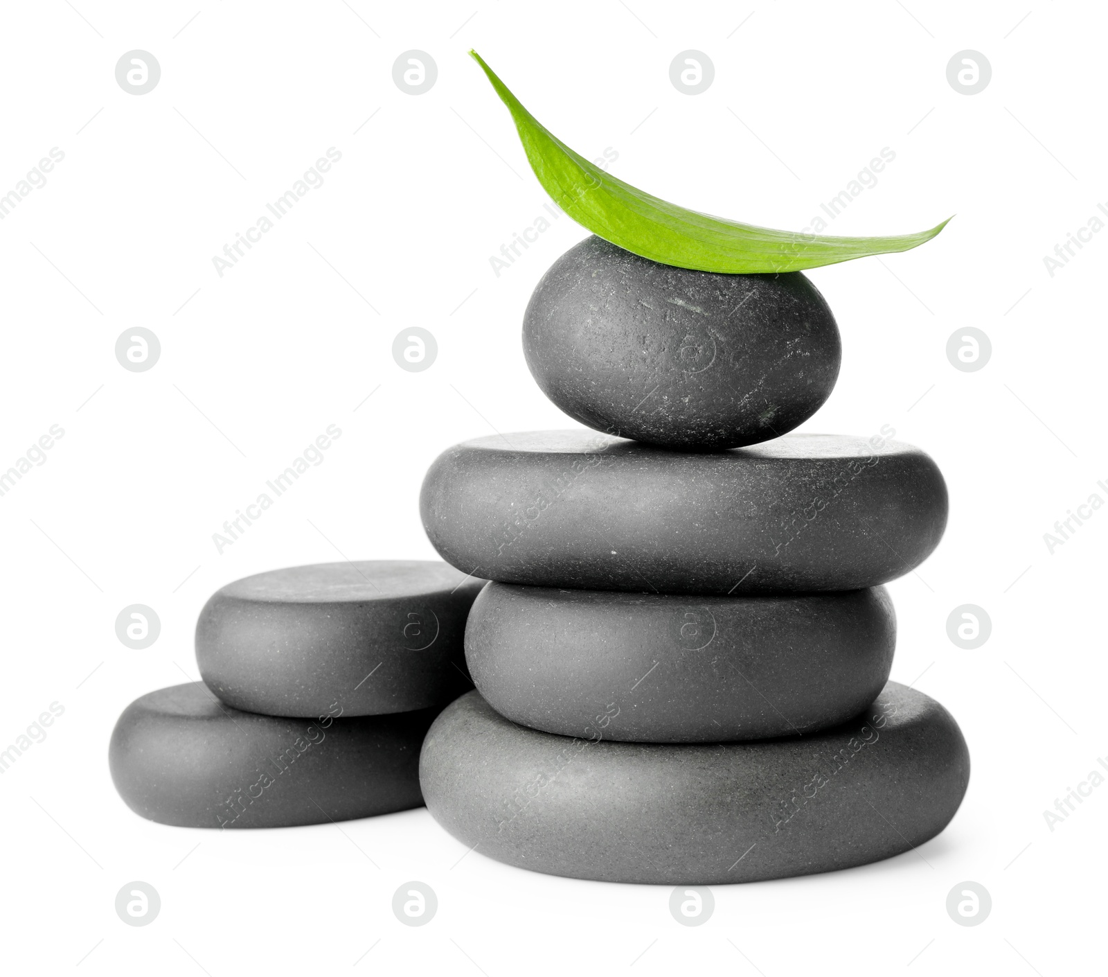 Photo of Stacked spa stones and green leaf isolated on white