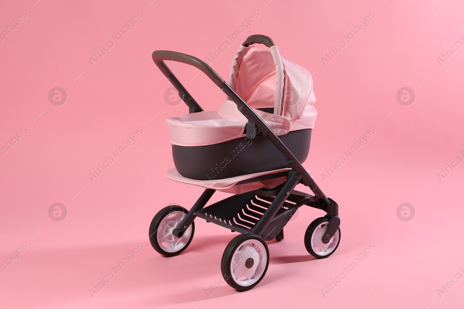 Photo of Stylish doll stroller on pink background. Kid's toy