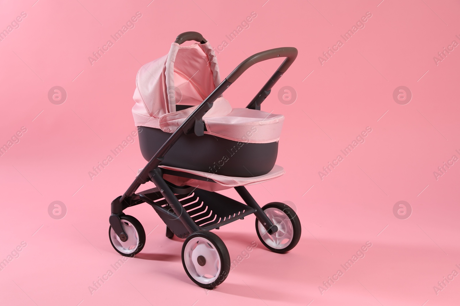 Photo of Stylish doll stroller on pink background. Kid's toy