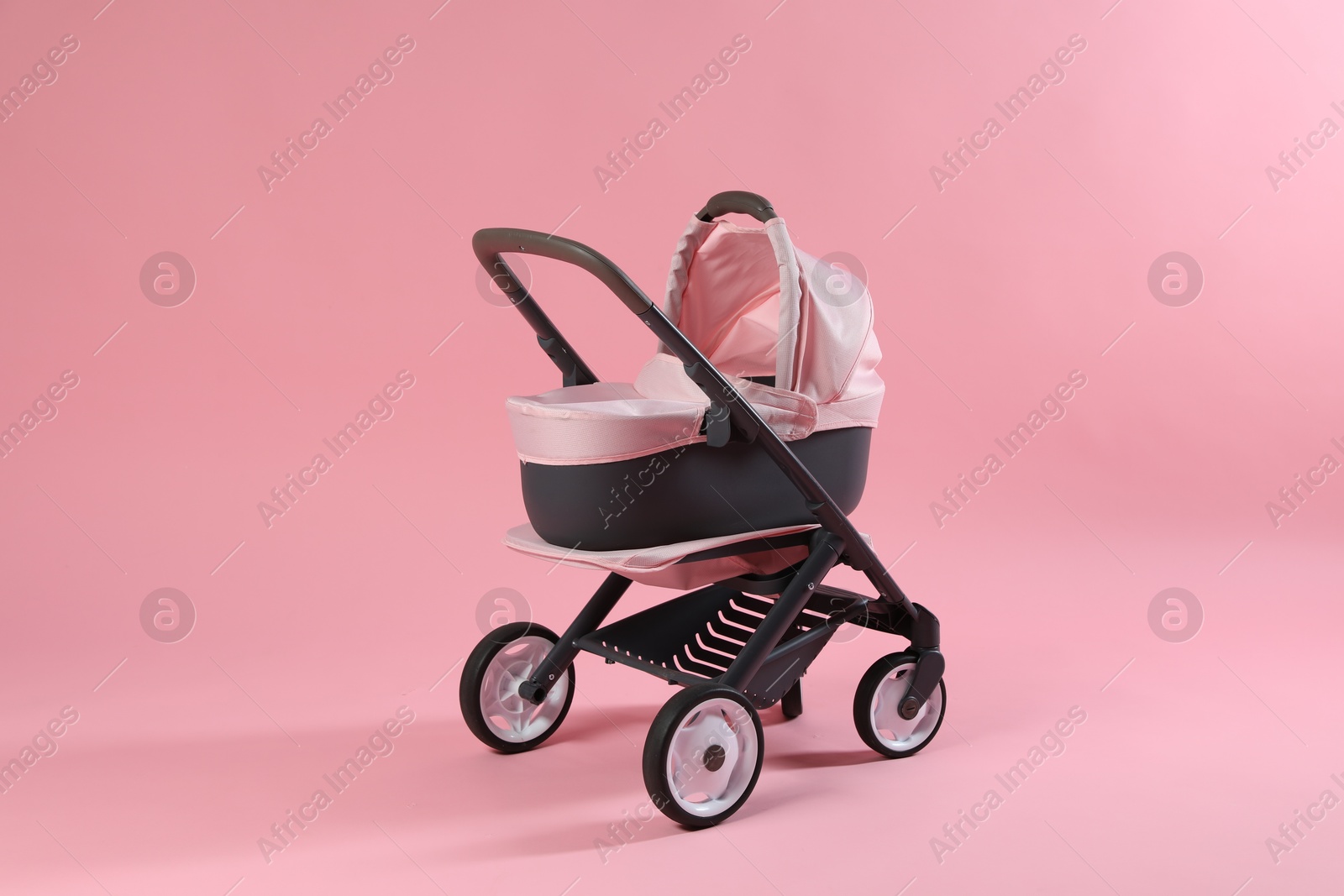 Photo of Stylish doll stroller on pink background. Kid's toy