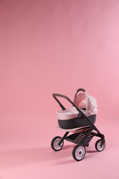 Photo of Stylish doll stroller on pink background, space for text. Kid's toy