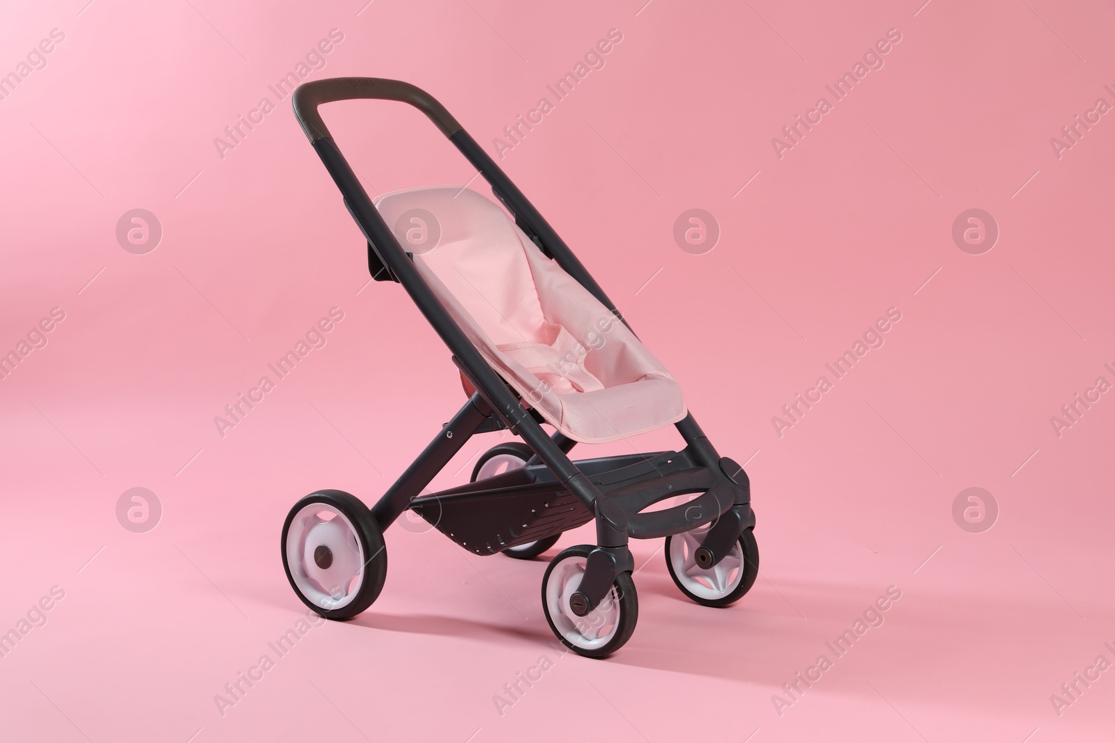 Photo of Stylish doll stroller on pink background. Kid's toy