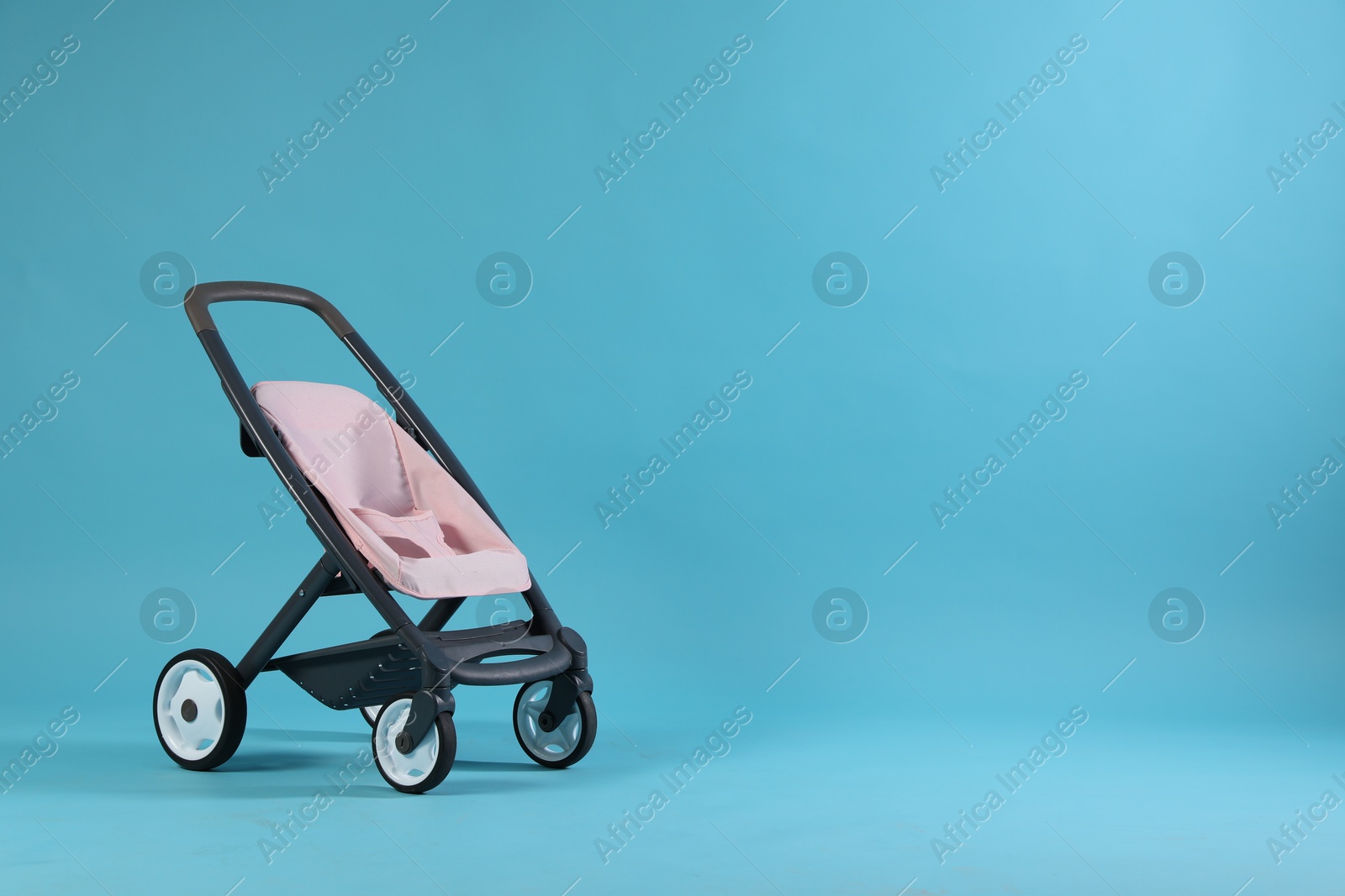 Photo of Doll stroller on light blue background, space for text. Kid's toy