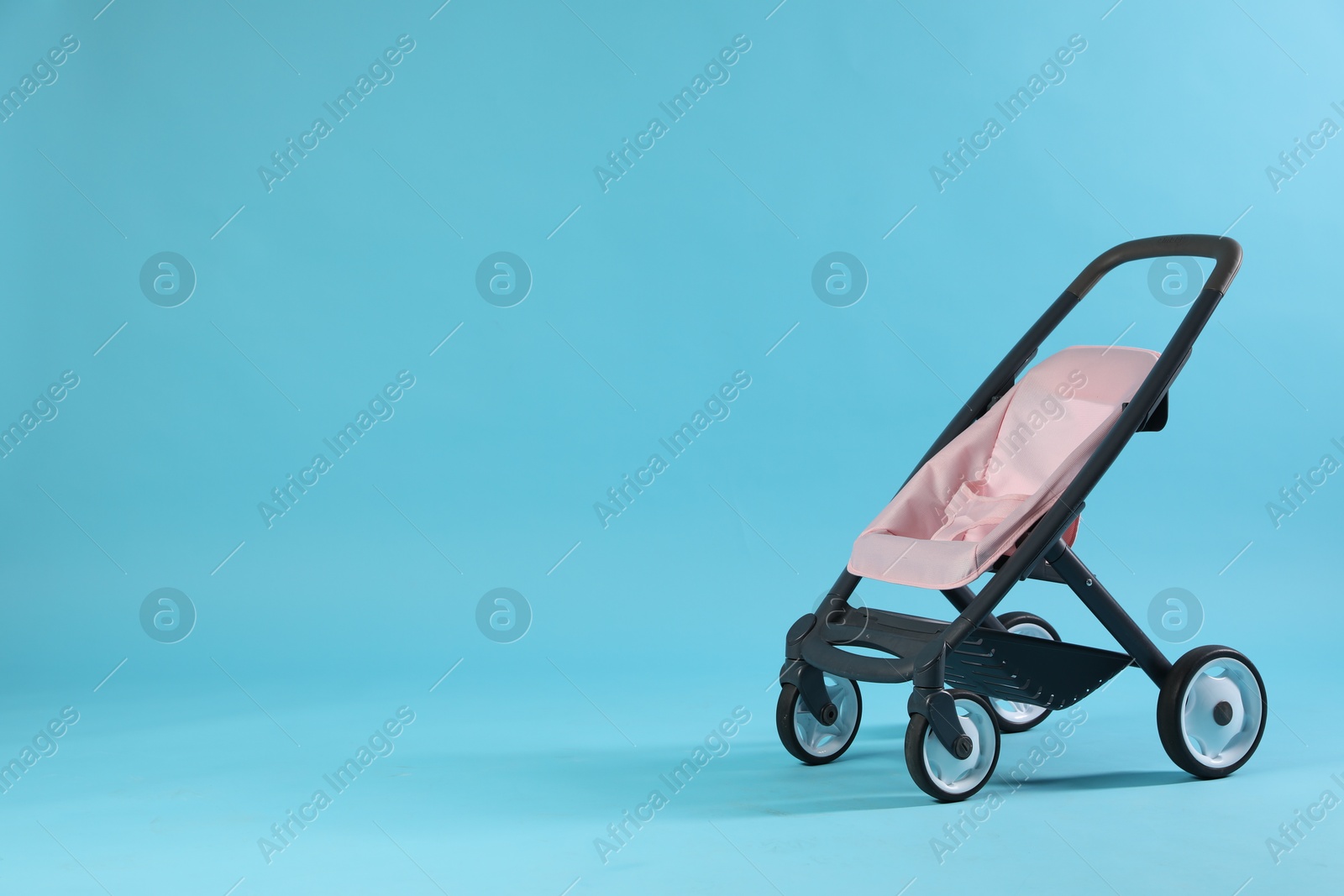 Photo of Doll stroller on light blue background, space for text. Kid's toy