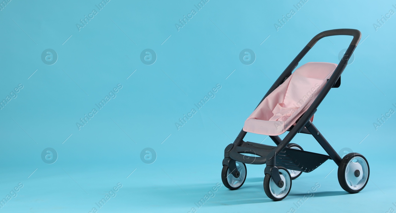 Photo of Doll stroller on light blue background, space for text. Kid's toy