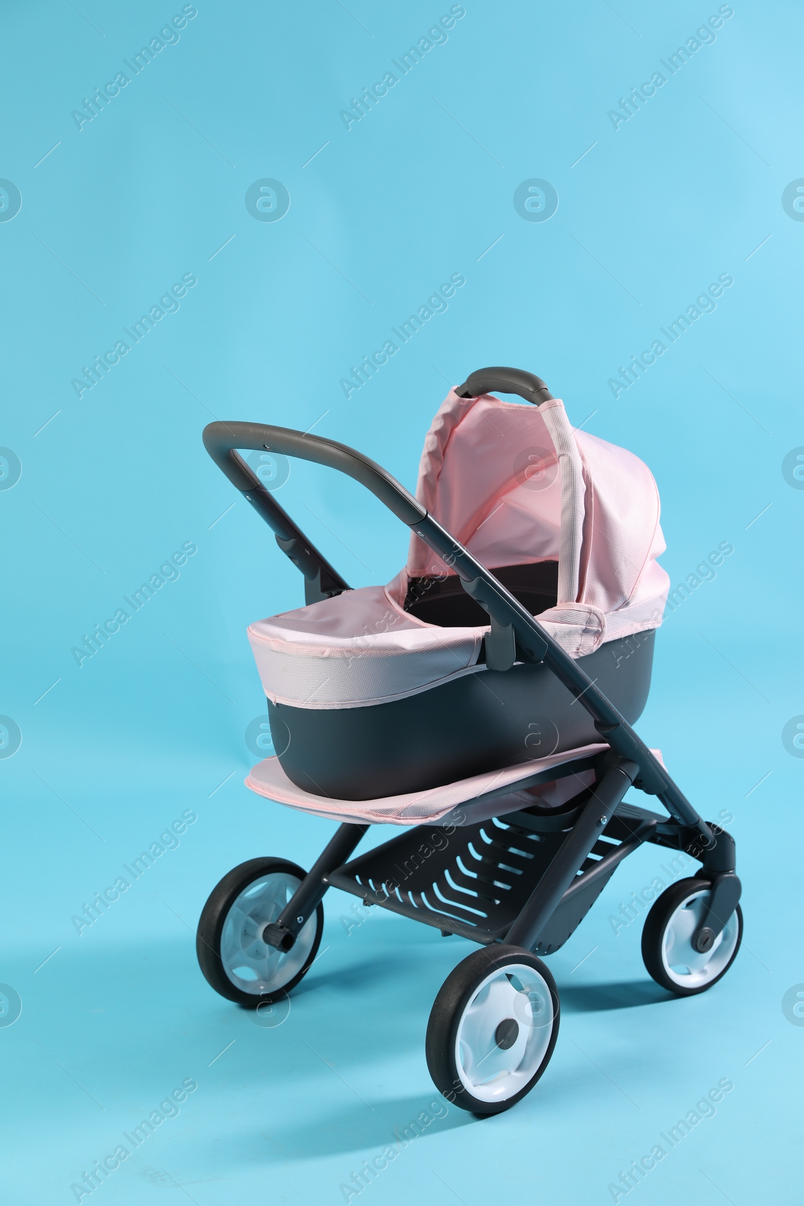 Photo of Doll stroller on light blue background. Kid's toy