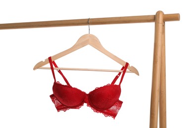 Photo of Hanger with red bra on wooden rack against white background