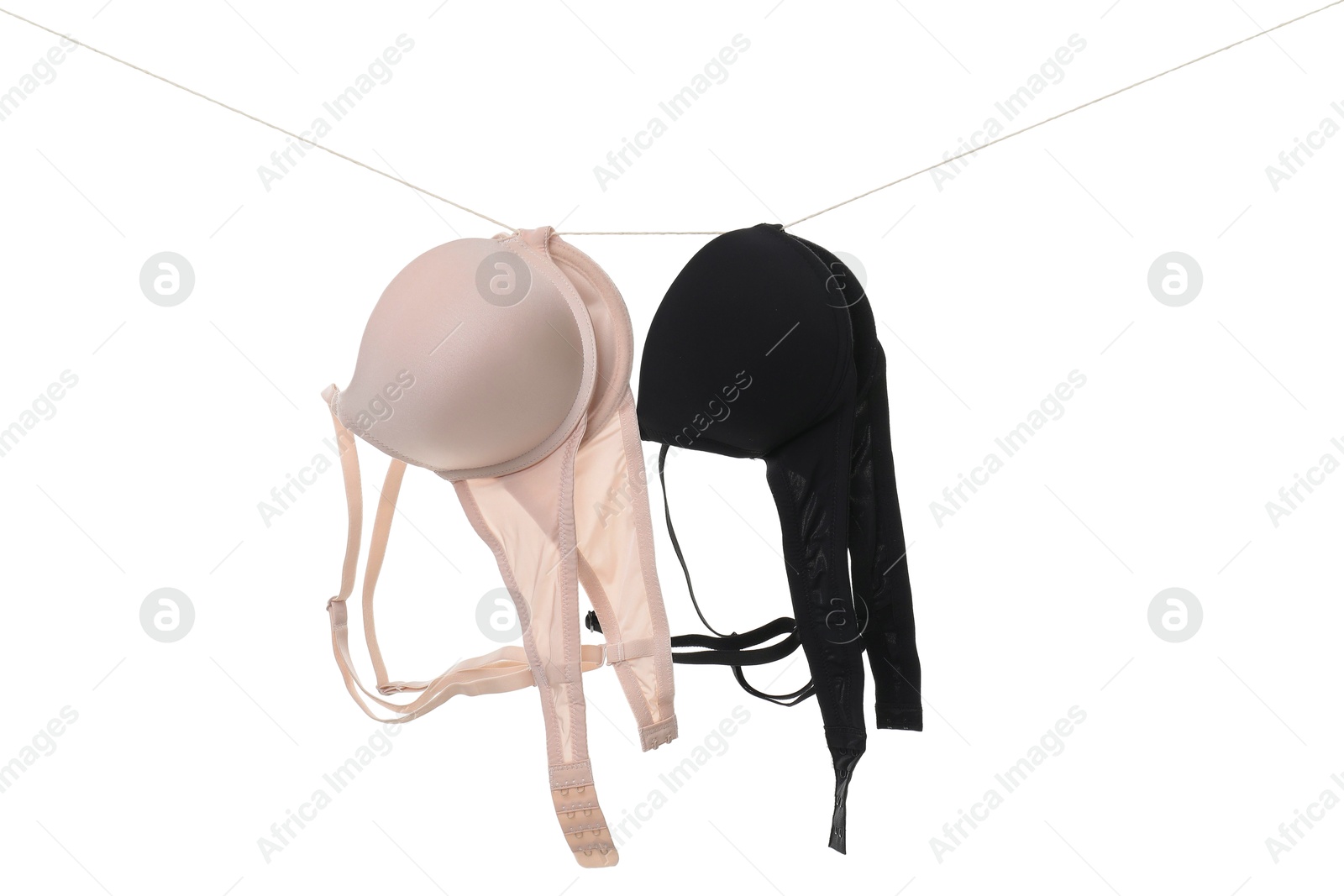 Photo of Beautiful bras hanging on rope against white background