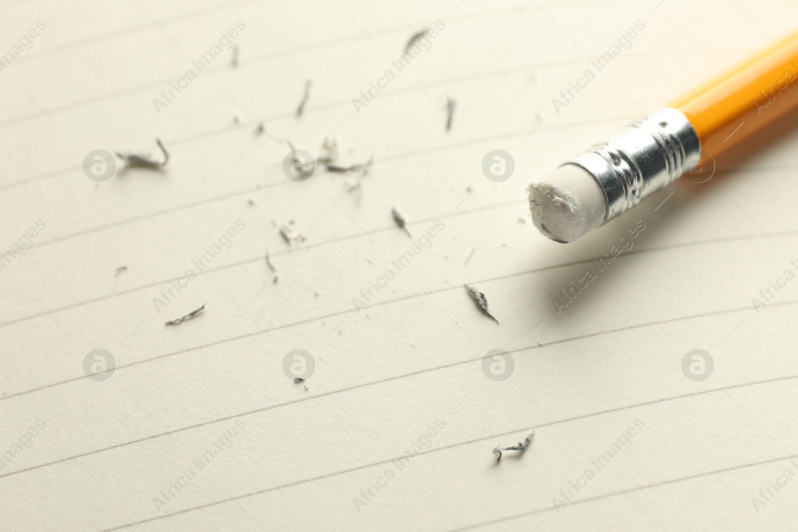 Photo of Pencil with eraser and scraps on white sheet of paper, closeup