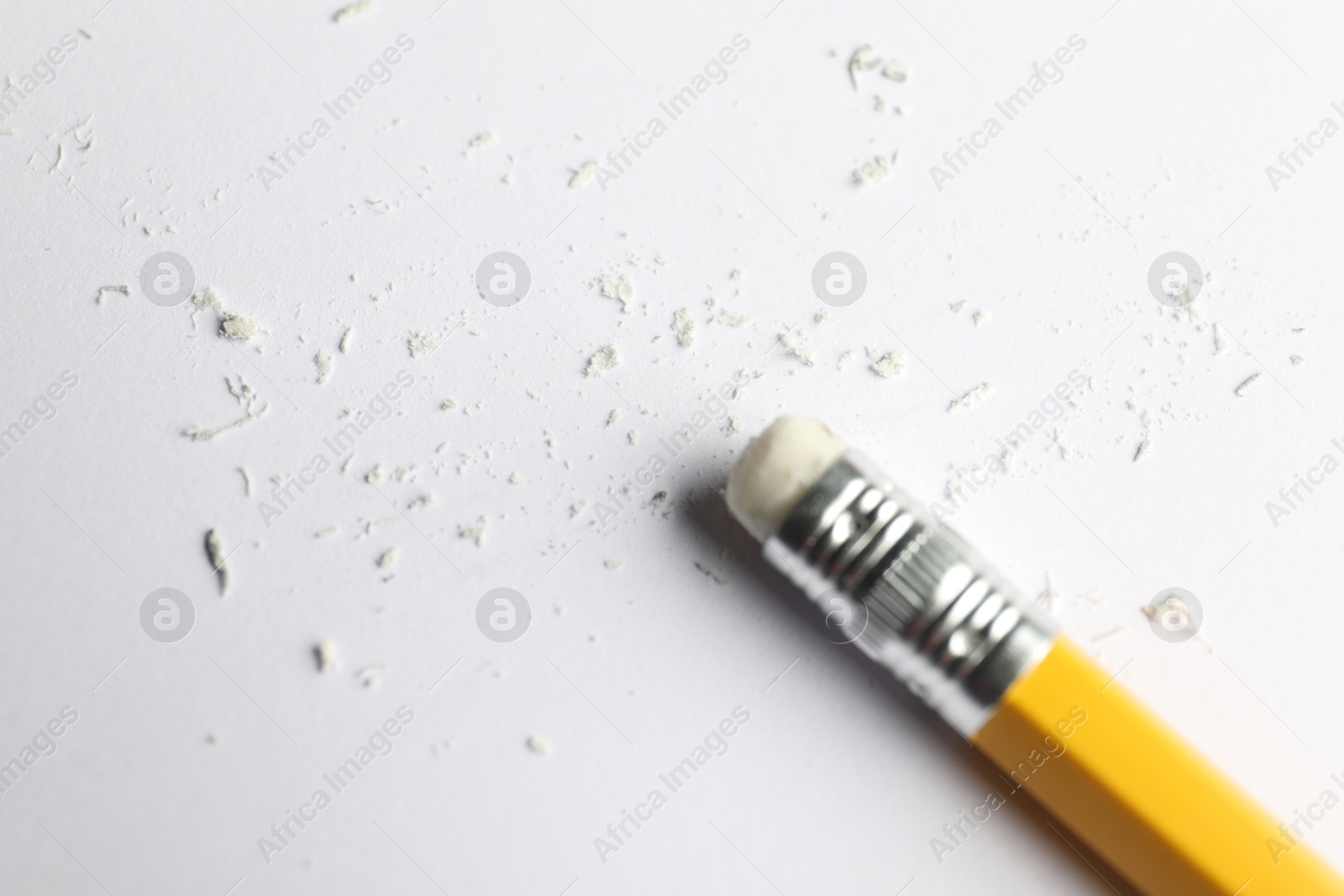 Photo of Pencil with eraser and scraps on white sheet of paper, above view