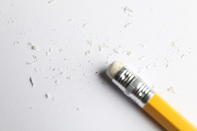 Photo of Pencil with eraser and scraps on white sheet of paper, above view