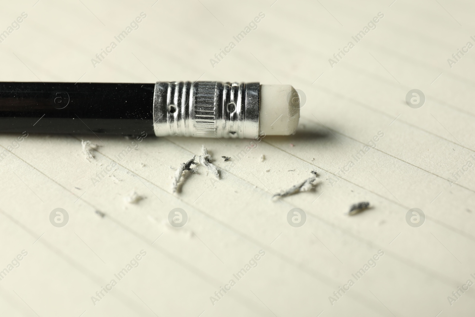 Photo of Pencil with eraser and scraps on sheet of paper, closeup