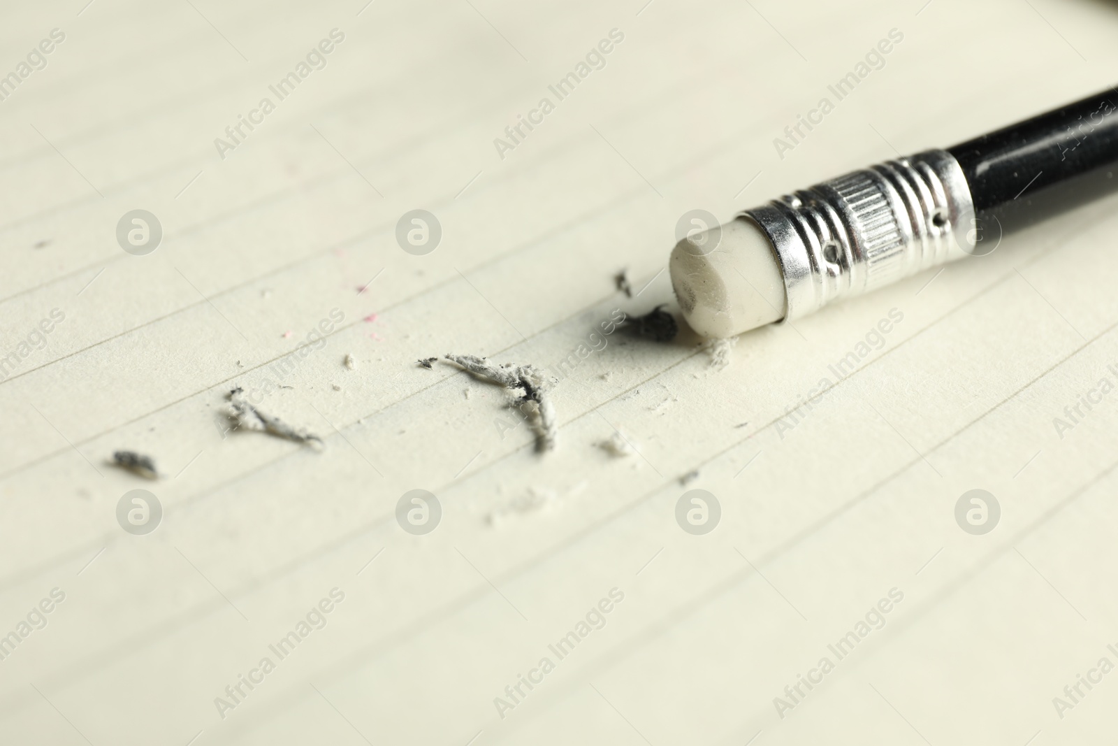 Photo of Pencil with eraser and scraps on sheet of paper, closeup