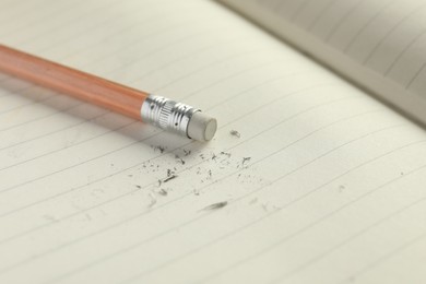 Photo of Pencil with eraser and scraps on copybook, closeup