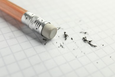 Photo of Pencil with eraser and scraps on white sheet of paper, closeup