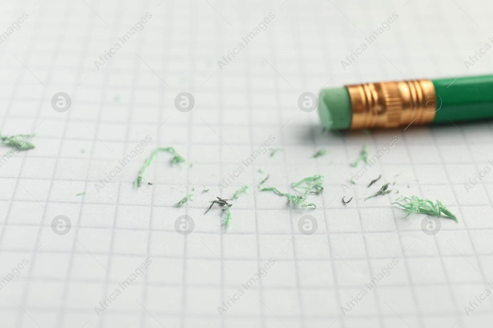 Photo of Pencil with eraser and scraps on white sheet of paper, selective focus