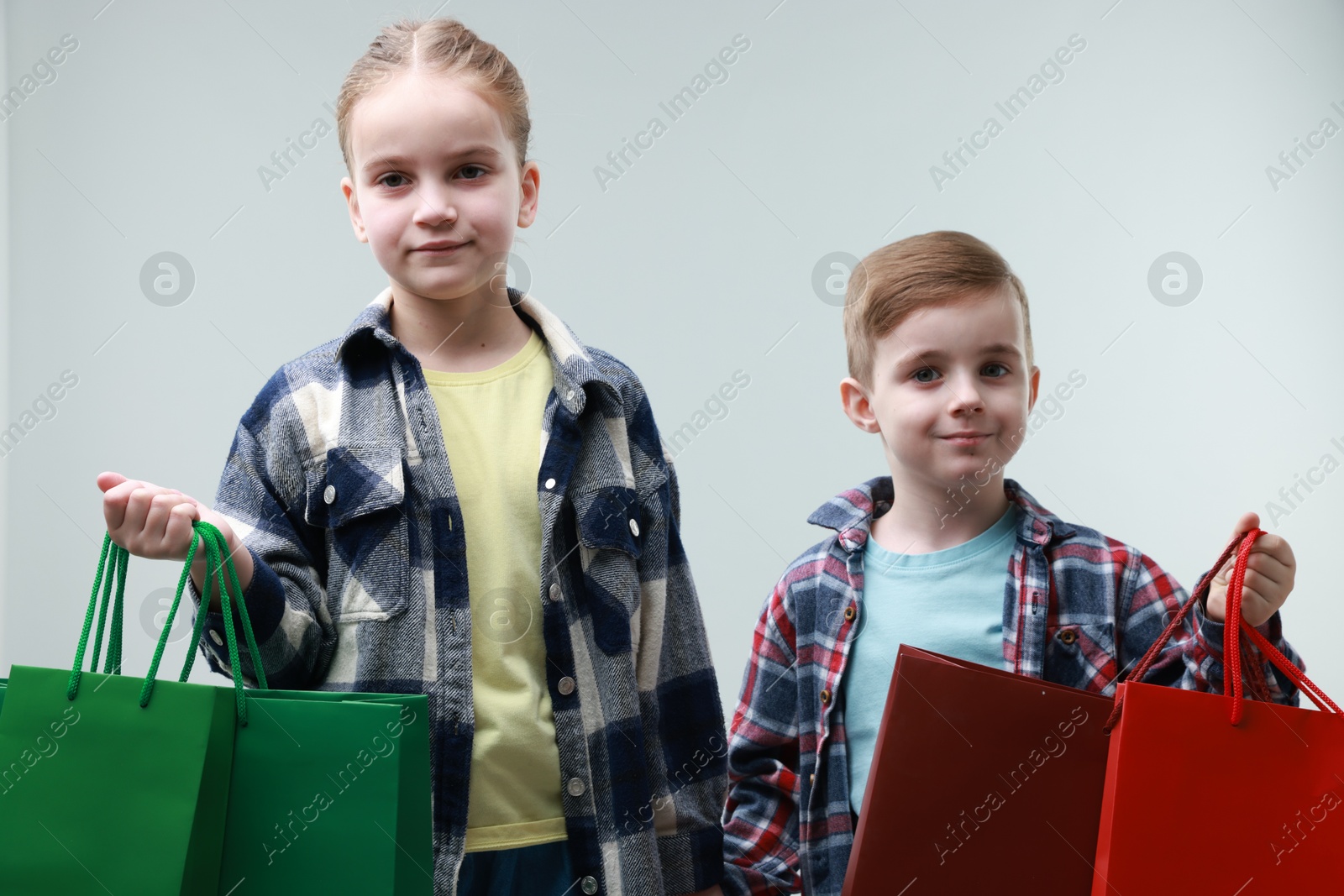 Photo of Cute little friends with shopping bags on grey background