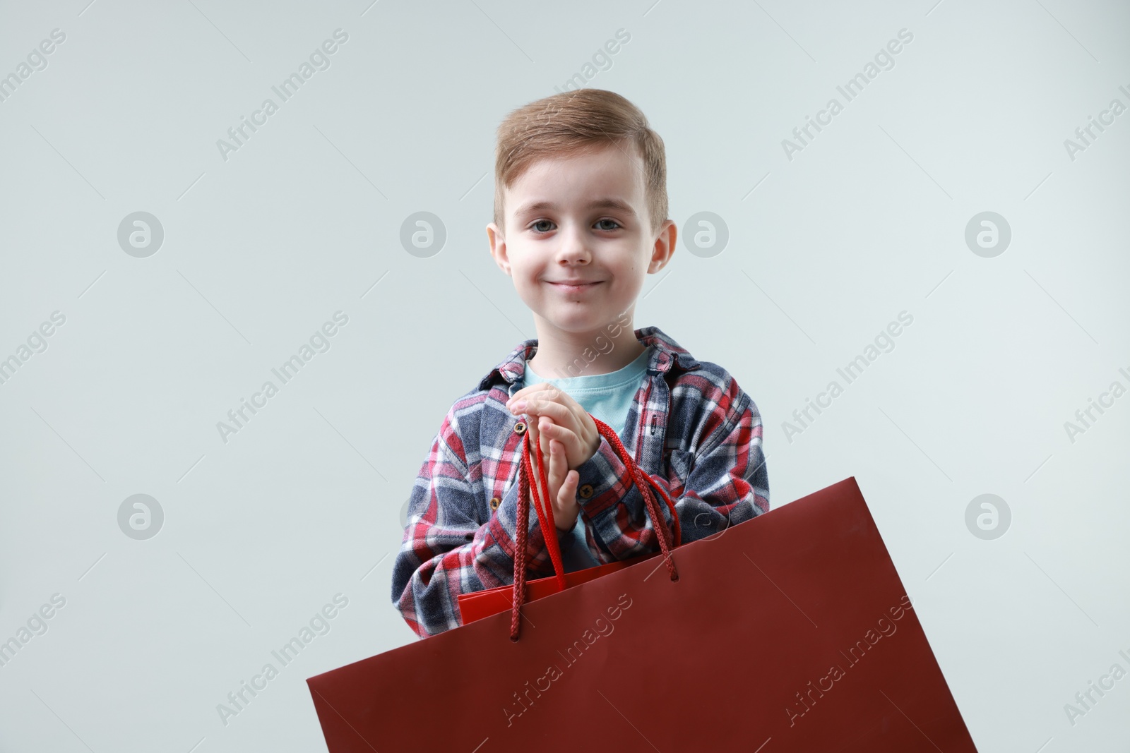 Photo of Cute little boy with shopping bags on grey background