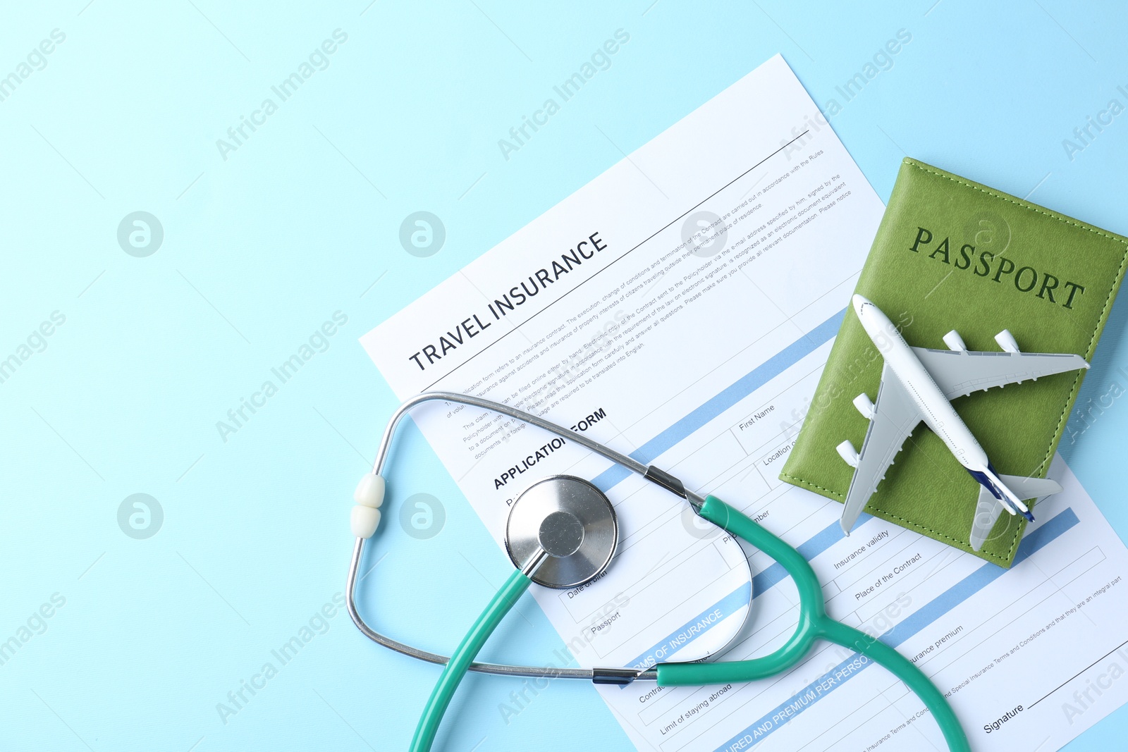 Photo of Medical tourism. Travel insurance application form, stethoscope, passport and plane model on light blue background, flat lay. Space for text