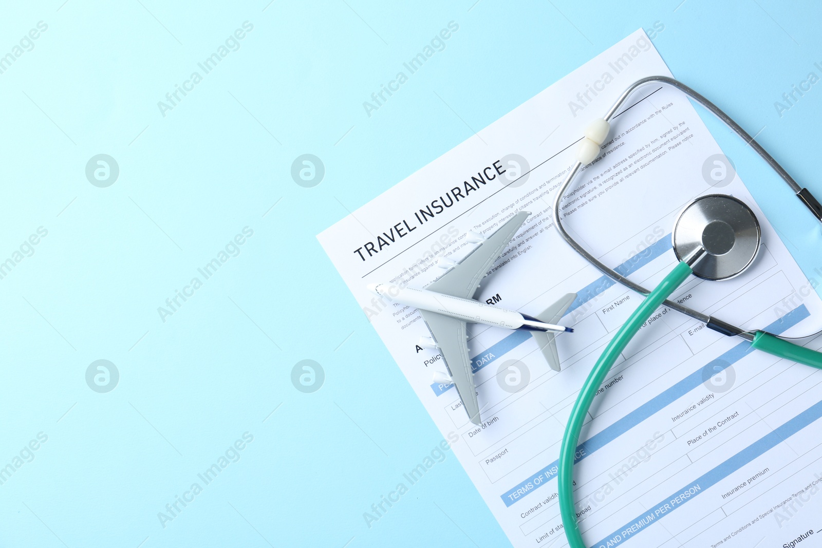 Photo of Medical tourism. Travel insurance application form, stethoscope and plane model on light blue background, flat lay. Space for text