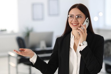 Portrait of banker talking on smartphone in office. Space for text