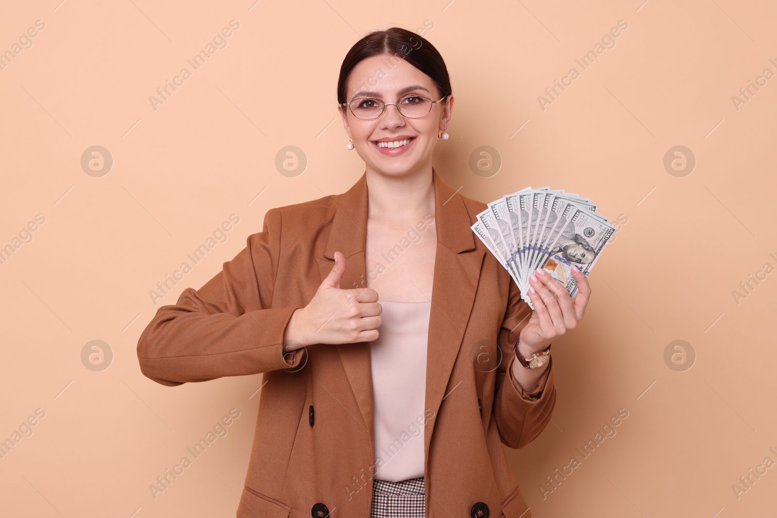 Photo of Banker with dollar banknotes showing thumbs up on beige background