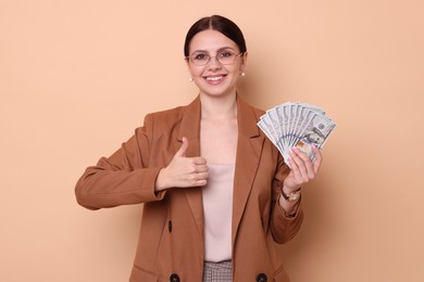 Photo of Banker with dollar banknotes showing thumbs up on beige background