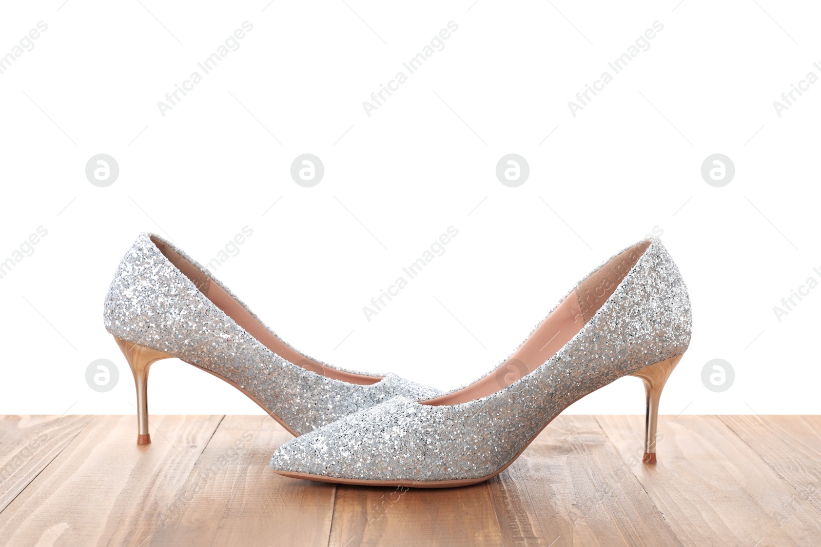 Photo of Beautiful high heeled shoes on wooden table against white background