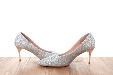 Photo of Beautiful high heeled shoes on wooden table against white background