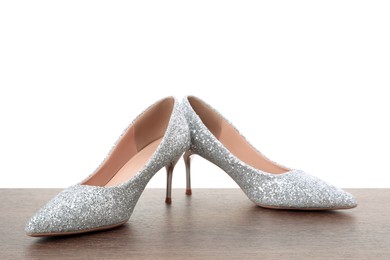 Photo of Beautiful high heeled shoes on wooden table against white background