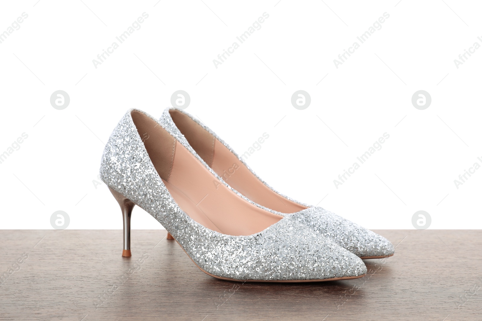 Photo of Beautiful high heeled shoes on wooden table against white background