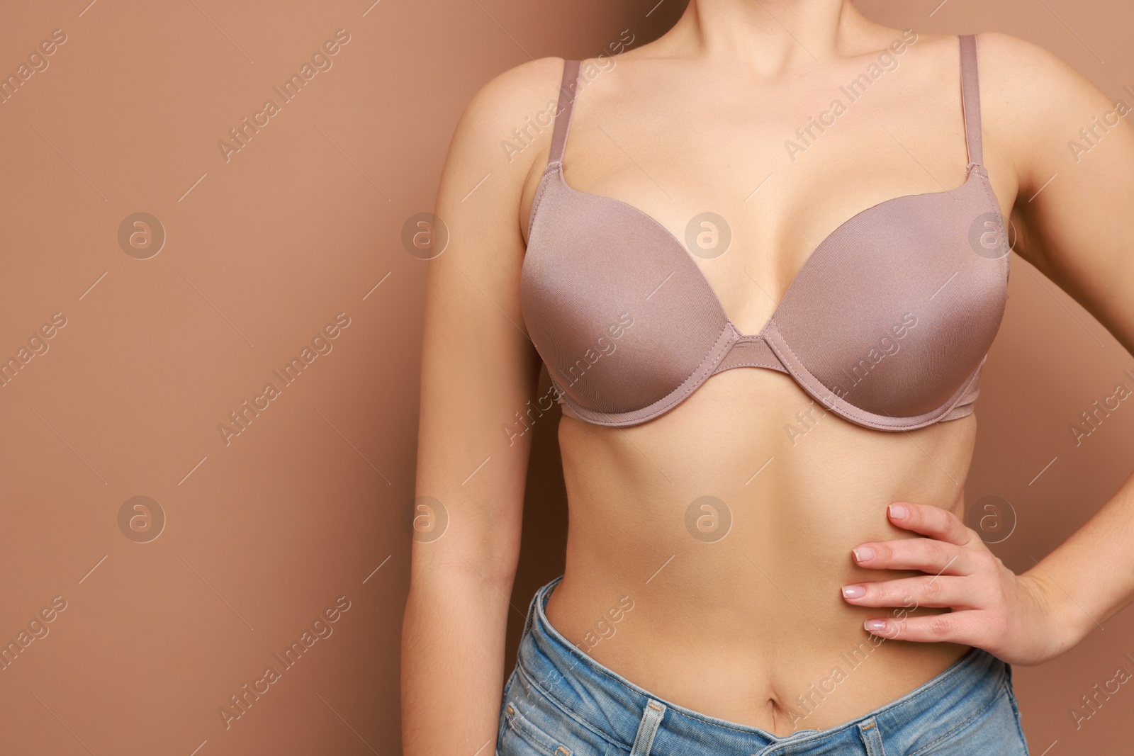 Photo of Woman wearing beautiful bra on beige background, closeup. Space for text