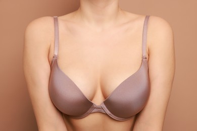 Photo of Woman wearing beautiful bra on beige background, closeup