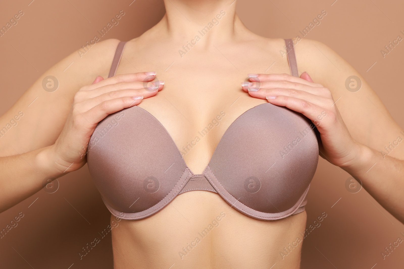 Photo of Woman wearing beautiful bra on beige background, closeup