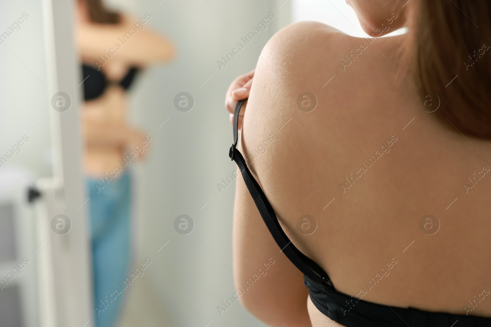 Photo of Woman adjusting strap of comfortable bra indoors, closeup