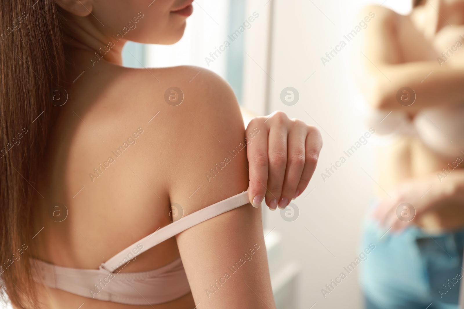 Photo of Woman adjusting strap of comfortable bra indoors, closeup