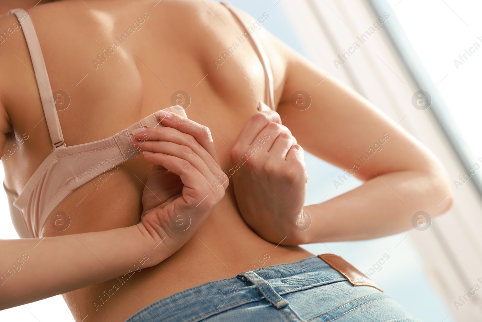 Photo of Woman putting on comfortable bra indoors, closeup