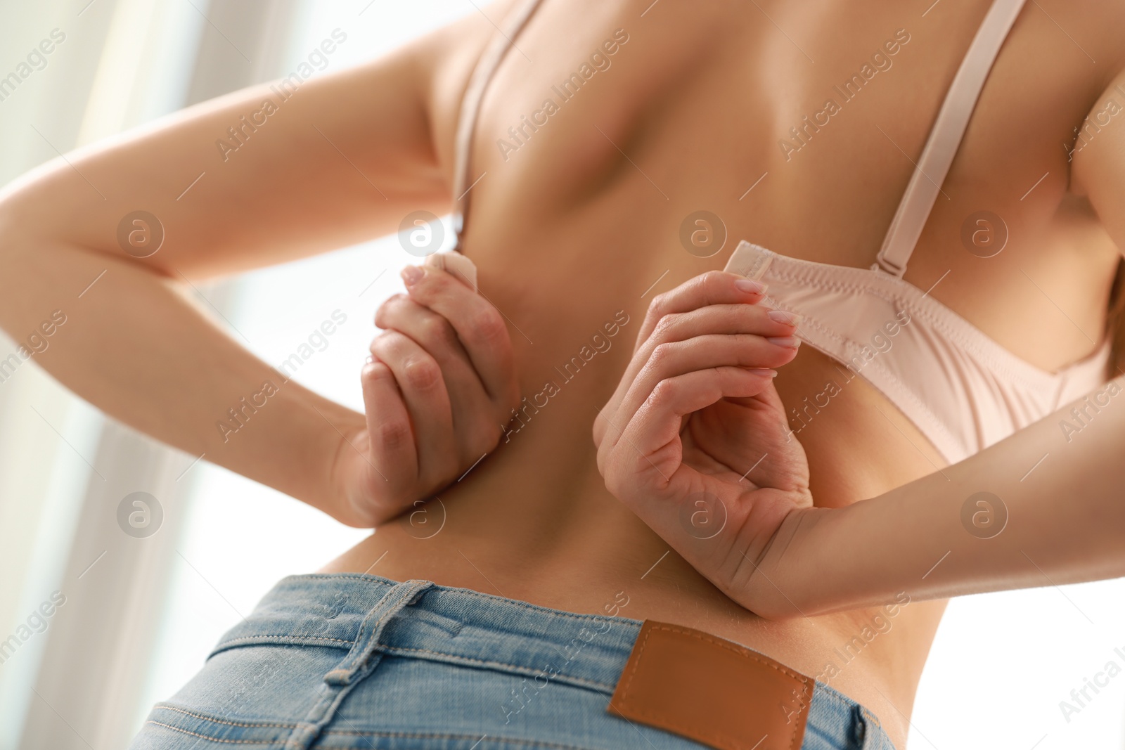 Photo of Woman putting on comfortable bra indoors, closeup