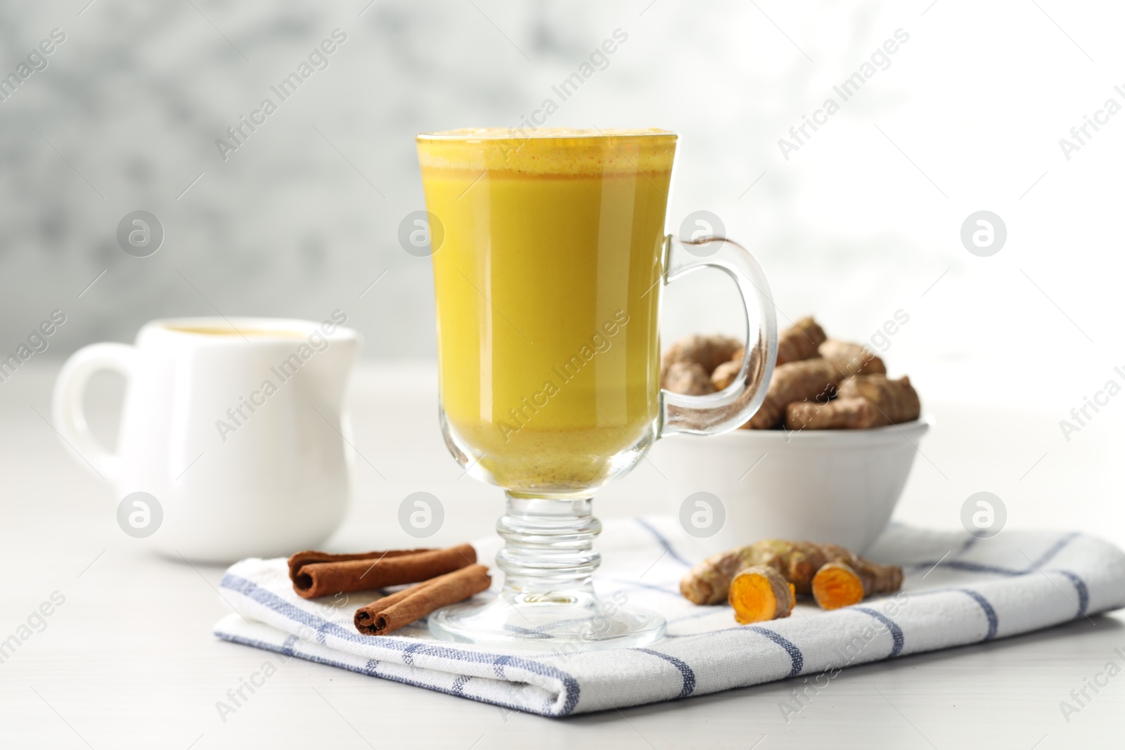 Photo of Delicious turmeric latte and rhizomes on white wooden table