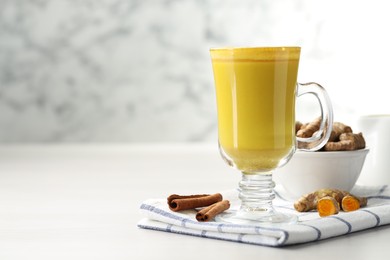 Photo of Delicious turmeric latte and rhizomes on white wooden table. Space for text