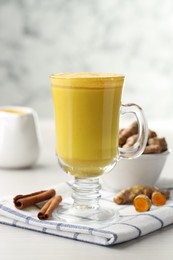 Photo of Delicious turmeric latte and rhizomes on white wooden table