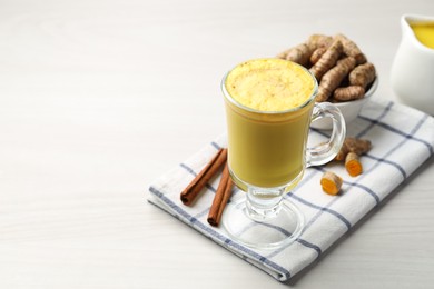 Photo of Delicious turmeric latte and rhizomes on white wooden table. Space for text