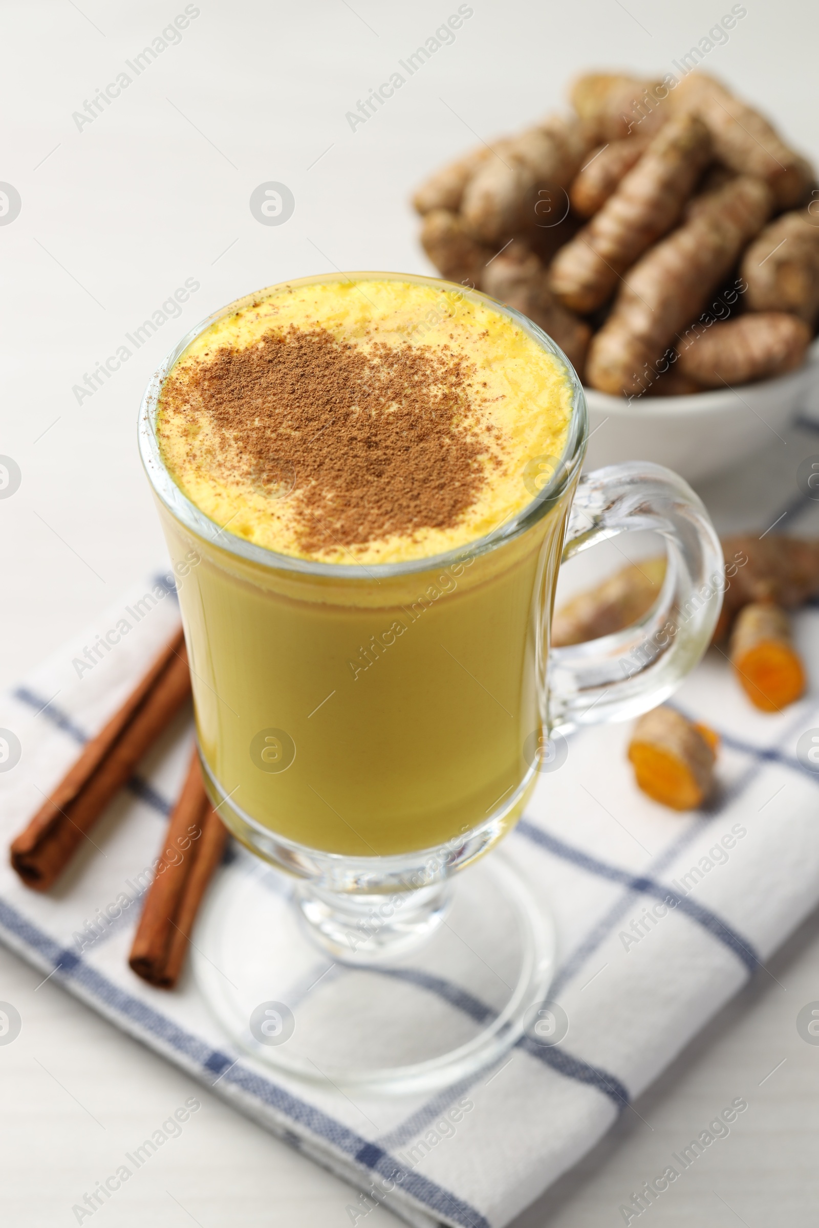 Photo of Delicious turmeric latte and rhizomes on white wooden table, closeup