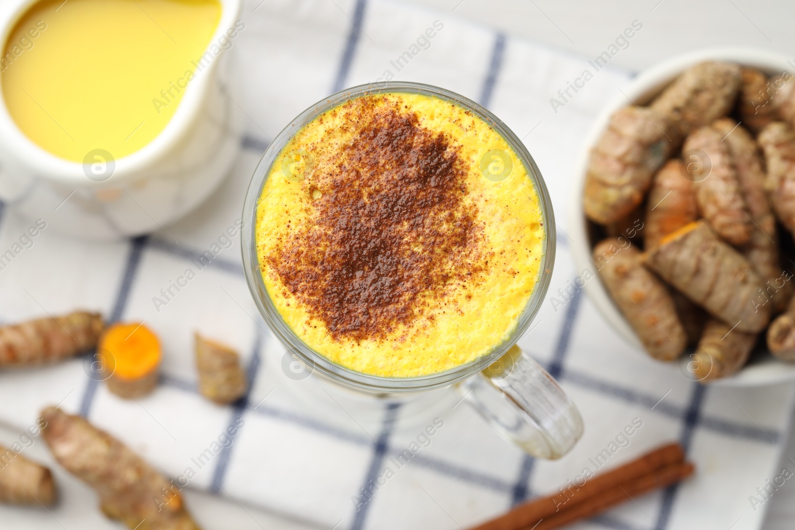 Photo of Delicious turmeric latte and rhizomes on white table, flat lay